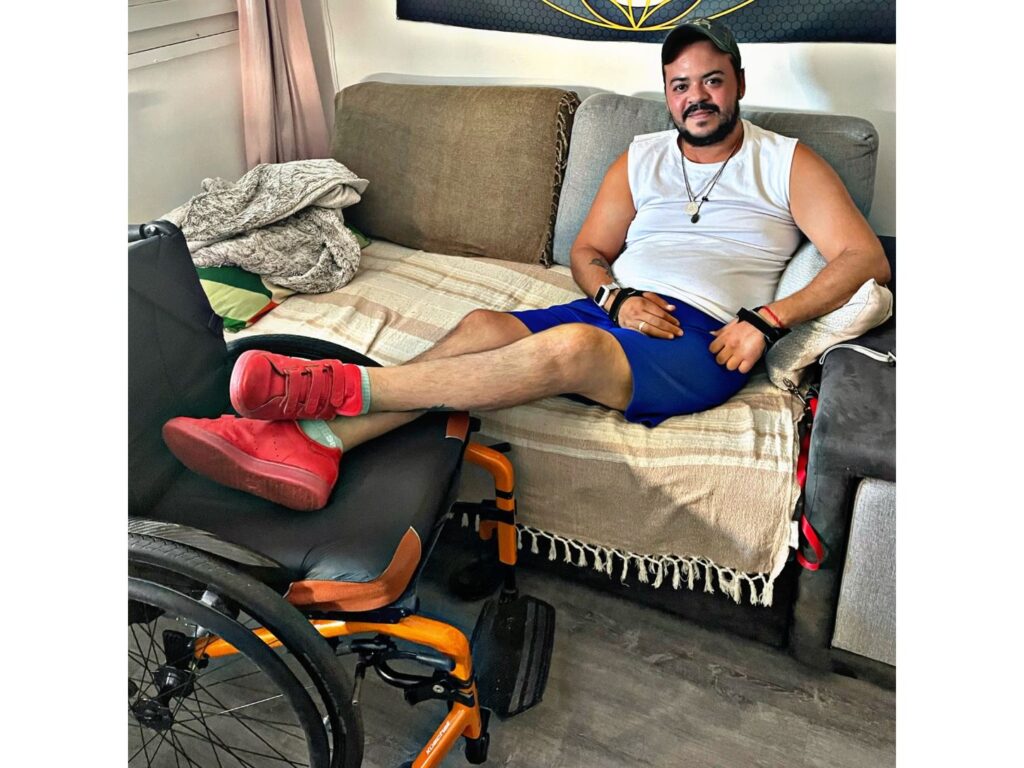 Daniel Salazar assis chez lui à côté de son fauteuil roulant, dans une scène personnelle illustrant son parcours de vie.